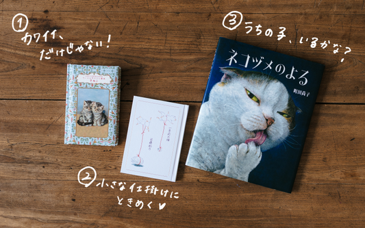 A cat book and two cards on a wooden surface.