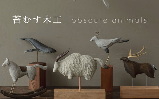 Wooden animal sculptures displayed on wooden bases against a neutral background.