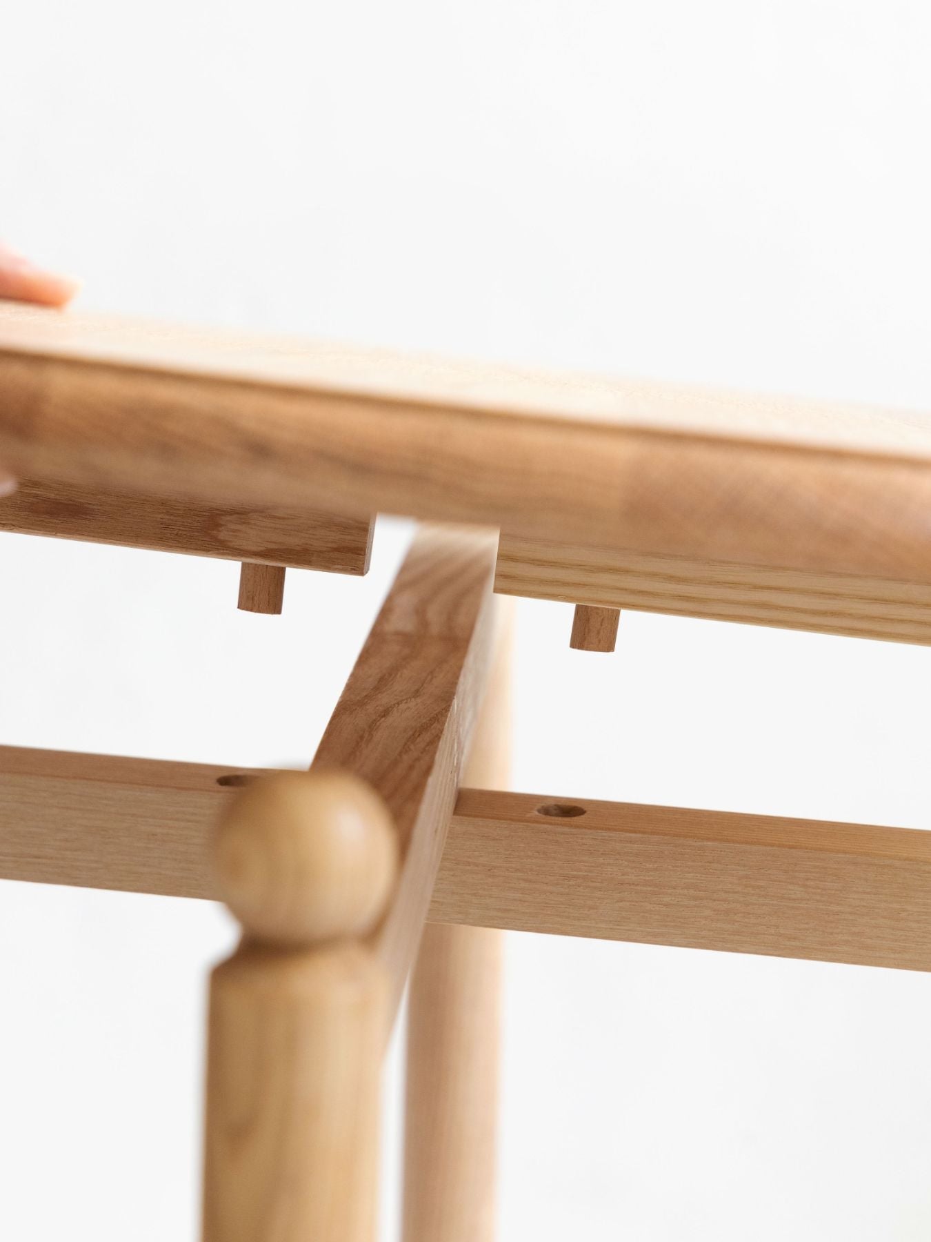 片側の脚のバーを天板中央の溝にはめ込み、もう片側の脚は、天板裏のダボと脚側のダボ穴を合わせて差し込むことで、両脚がしっかりと固定されます。